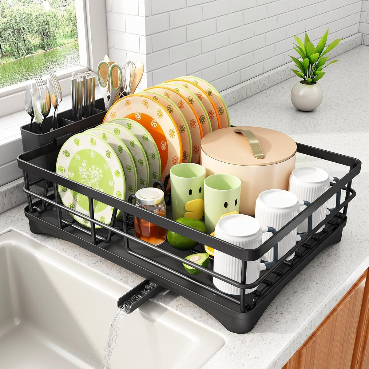 ComfyHome black single-tier dish drying rack with drainboard, side drain outlet and utensil holder beside a kitchen sink